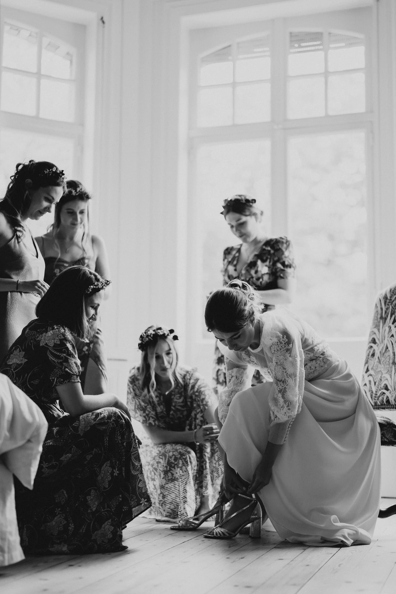 La mariée entourée de ses proches pendant les préparatifs, en noir et blanc.