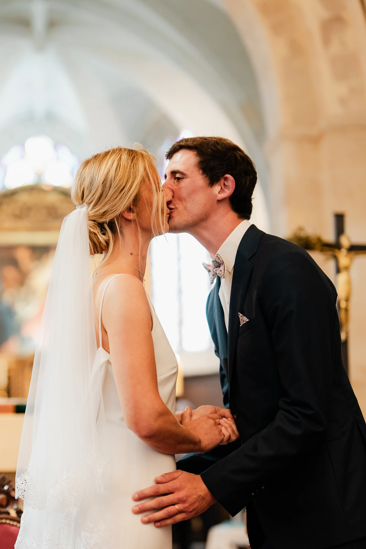 Le baiser des mariés dans la lumière de l’église.