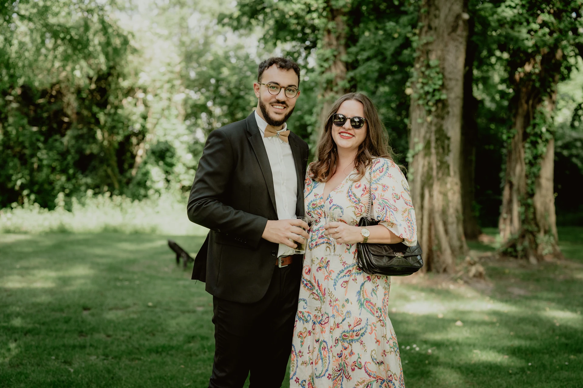Deux invités posent avec leurs verres dans le jardin pendant le vin d’honneur.