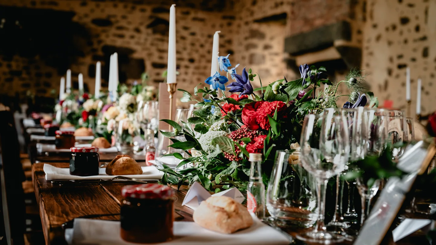 Table de réception de mariage ornée de fleurs, de bougies et de verres.