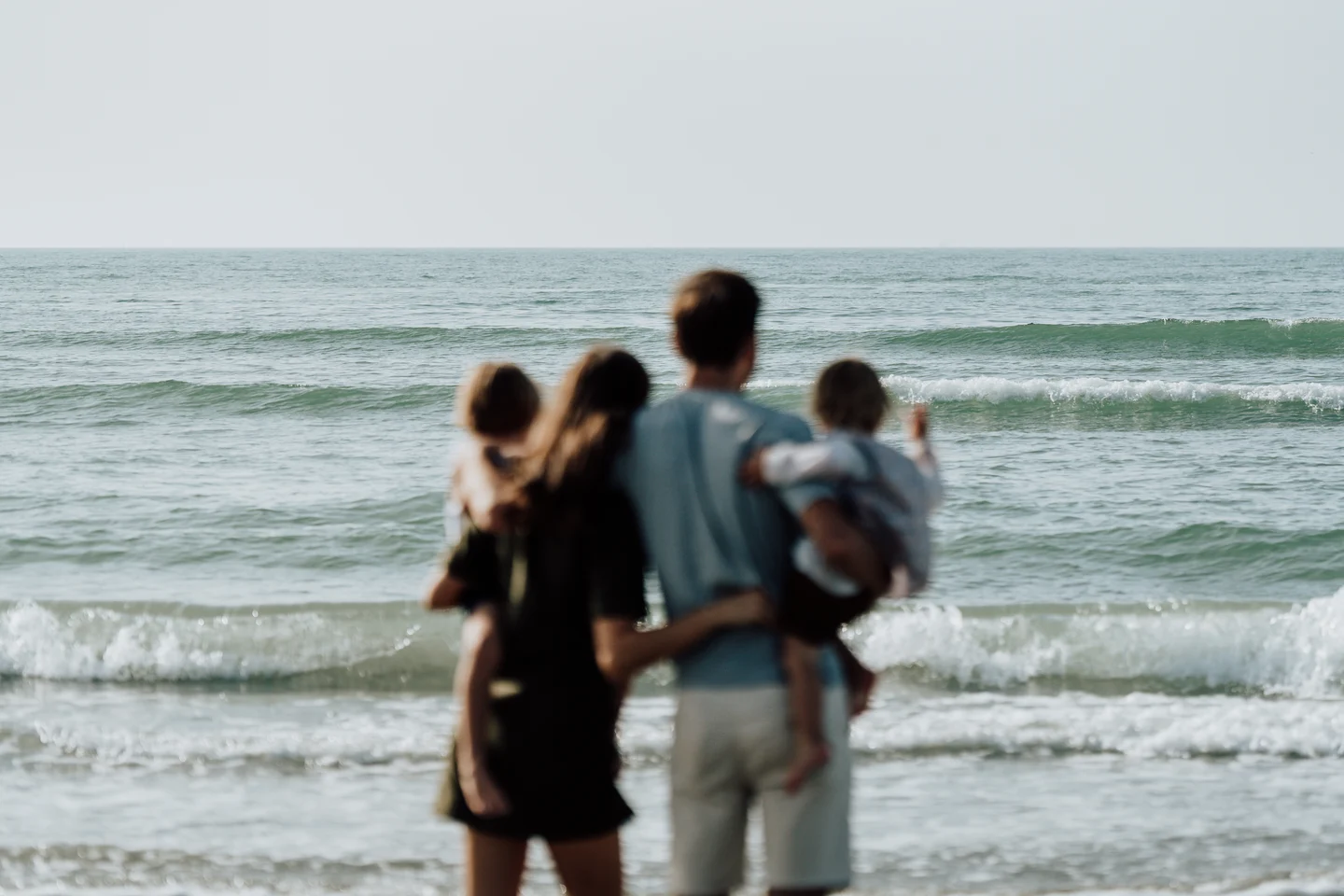 Parents et enfants réunis face à la mer lors d’une séance photo en famille.